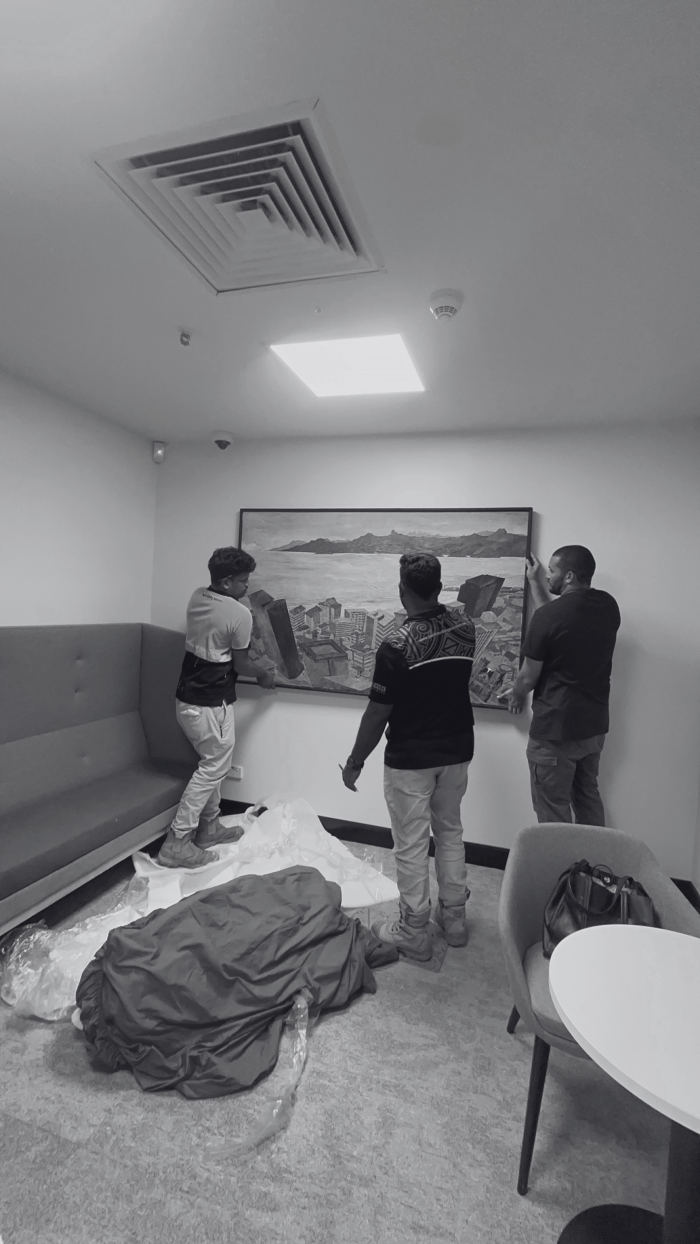 The TAD crew hanging a large painting in an office